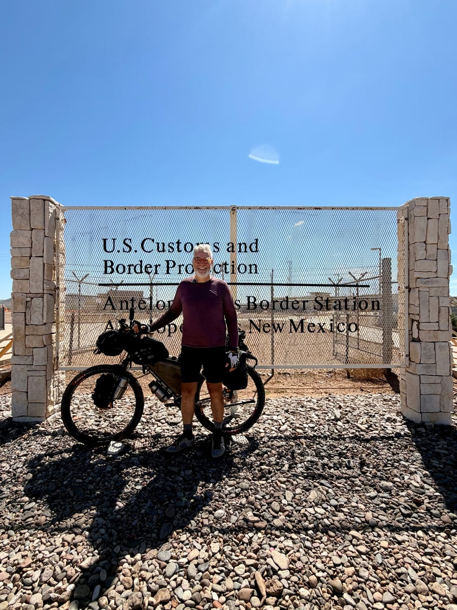 Robin with his loaded bike at the Antelope Wells Border Station sign, New Mexico — the southern terminus of the GDMBR